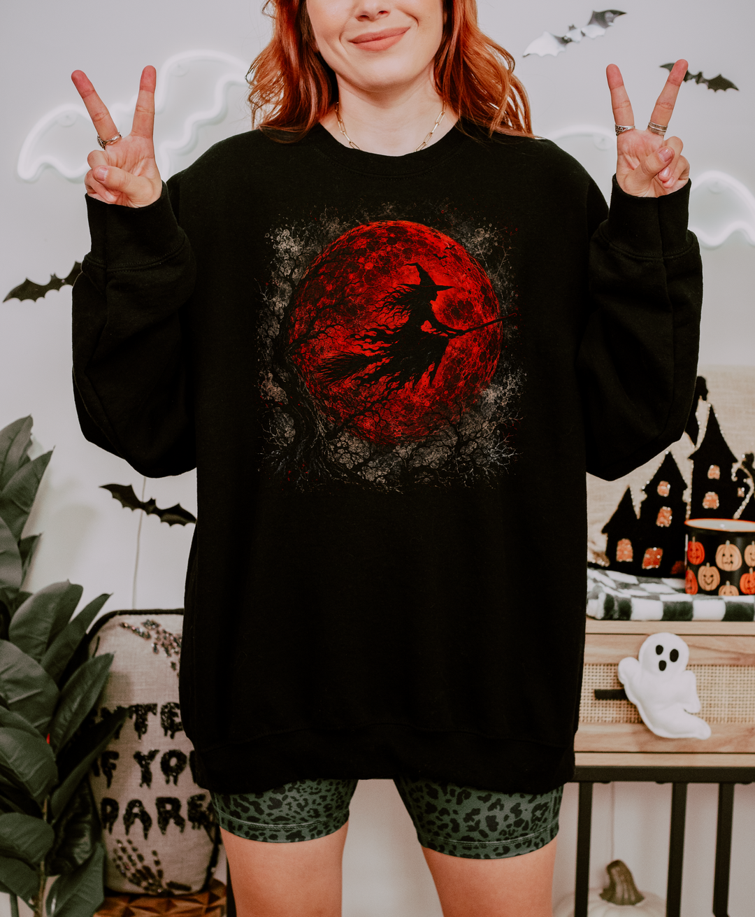 Black Gildan crewneck sweatshirt with a red moon and flying witch graphic